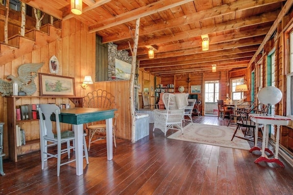 L’intérieur d’un chalet en bois comprend un coin repas, des étagères et un escalier.