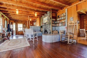 Un intérieur en bois avec une cheminée, des étagères à livres et une table ronde.