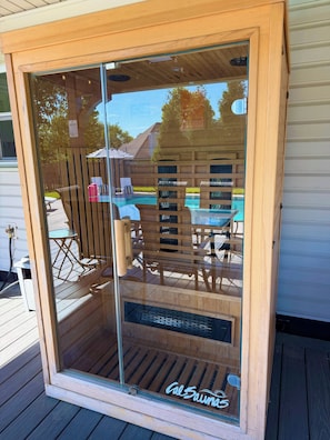 A wooden-framed glass door leading to a deck with outdoor furniture and a pool.