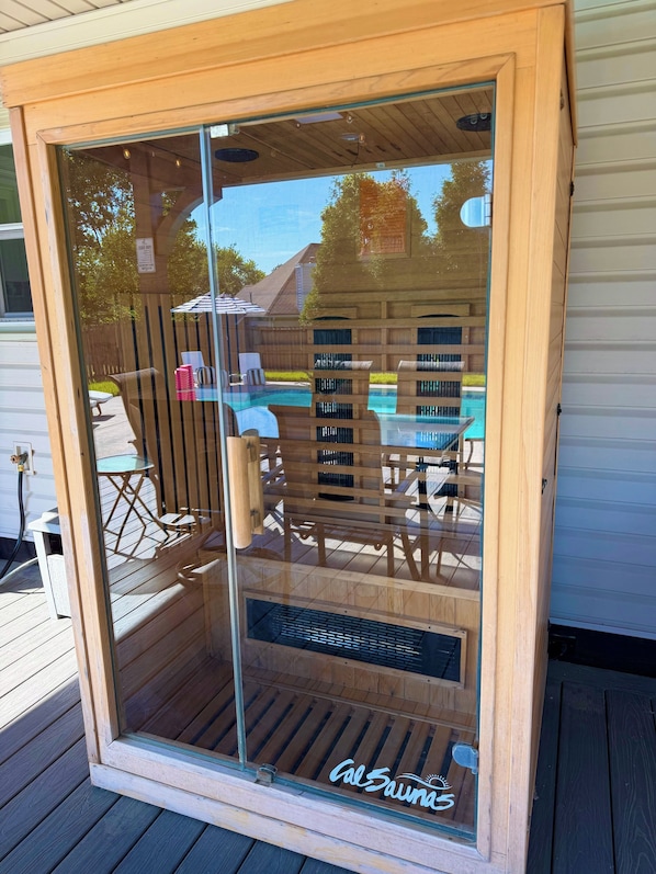 A wooden-framed glass door leading to a deck with outdoor furniture and a pool.