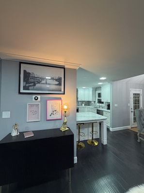 A modern living room with a black console table, framed artwork, and a decorative lamp.