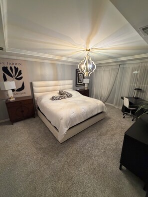 Une chambre à coucher avec un grand lit, un lustre, un bureau et une table de chevet.