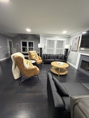 A modern living room with a fireplace, leather sofas, and a round coffee table.