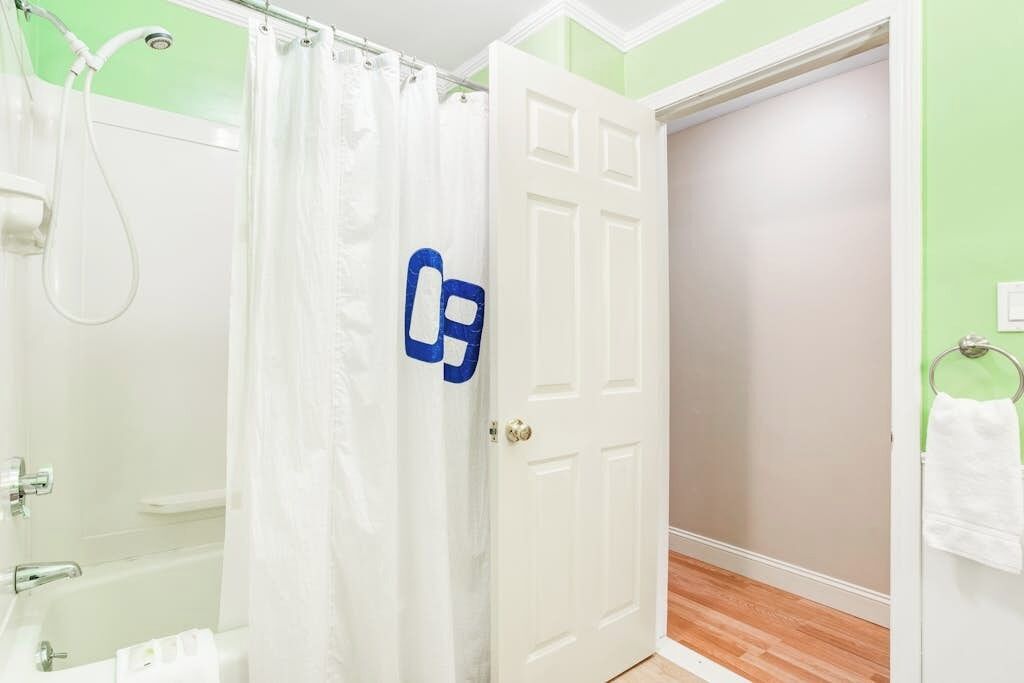Une salle de bain avec une douche, des toilettes et une porte sur laquelle est accrochée une serviette.
