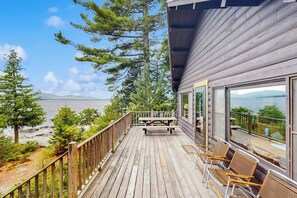 Une terrasse en bois avec vue sur la mer, une table de pique-nique et des sièges.