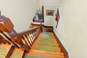 Eine Holztreppe mit Handlauf, Teppichstufen und Blick auf eine Terrasse.
