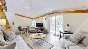 A spacious living area with a sofa, coffee table, TV, and dining table. - Geodesic Dome w/ Riverfront Deck, Lovely Views, & High-Speed WiFi - Dogs Welcome (Boothbay)
