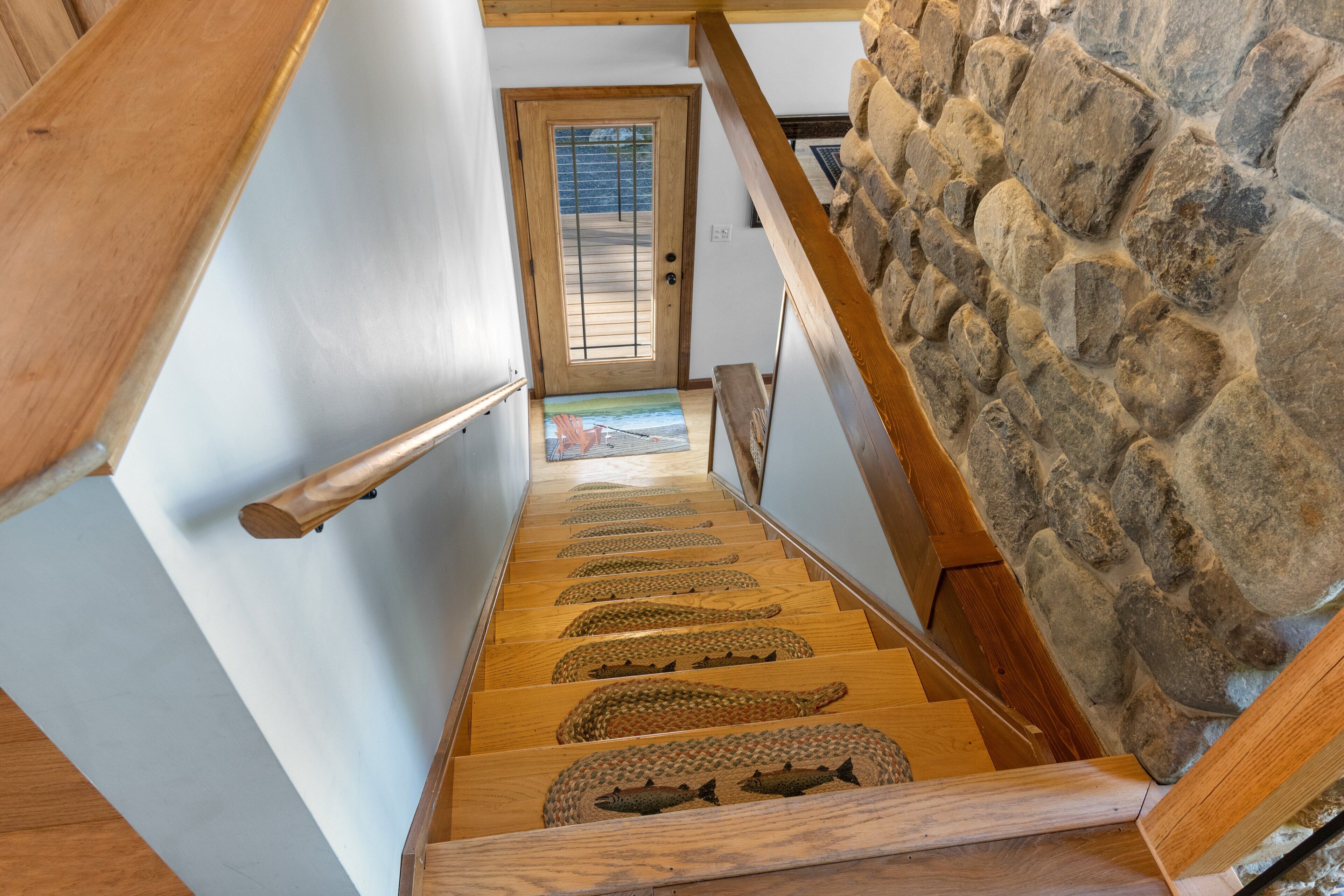 A wooden staircase with a stone wall on one side and a door at the top.