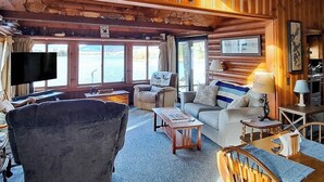 Un interior de cabaña con un sofá, un sillón y un televisor.