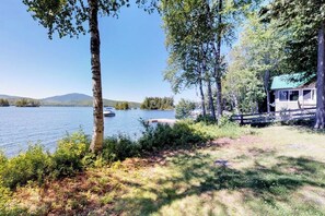 A lakeside cabin with a dock, surrounded by trees and a clear view of the lake.