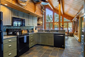 A modern kitchen with granite countertops, stainless steel appliances, and a large island. - Lakeside Lodge with Amazing Water Views, Screened Porch, Dock, & Firepit (Greenville)