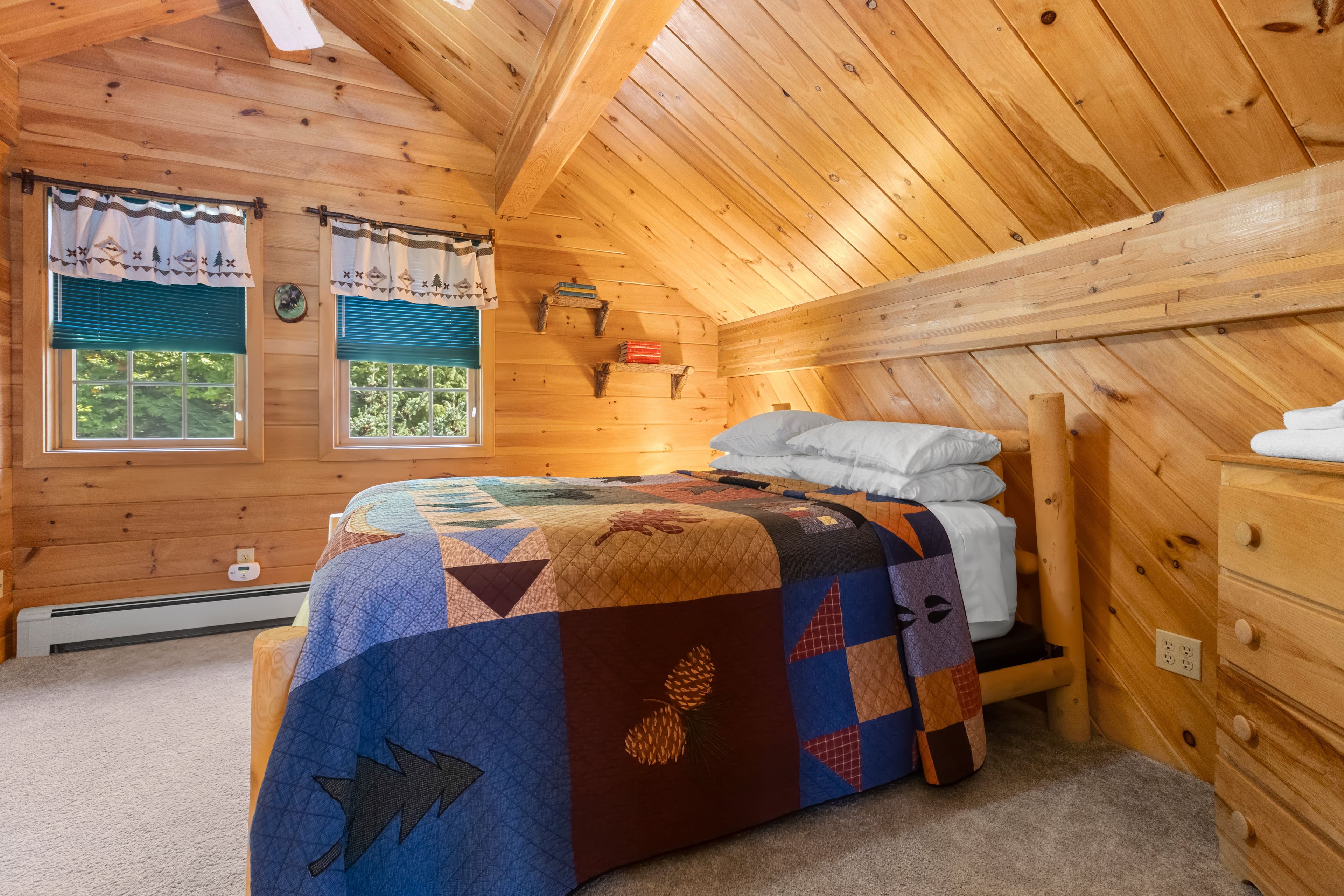 A wooden cabin bedroom with a bed, windows, and a quilt.