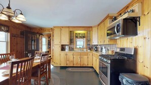 A wooden kitchen with a dining area, a stove, and a trash bin.
