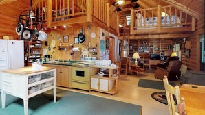 A rustic cabin interior with a kitchen, dining area, and loft space. - Dog-Friendly Lakefront Log Cabin with Peaceful Atmosphere, Dock & Boat Launch (Rockwood)