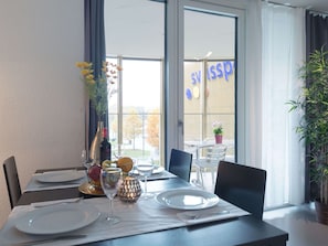 A dining area with a table set for two, a vase with flowers, and a view of the outside. - Apartment  by Interhome (Lucerne)