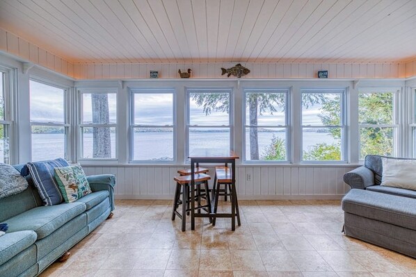 Ein Zimmer mit Seeblick, einem Holztisch mit Hocker und zwei Sofas.