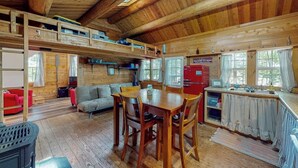 Een houten chalet met een eethoek, keuken en een slaapgedeelte op de bovenverdieping.