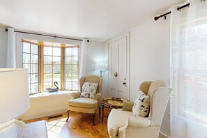 A room with a large window, two armchairs, a small table, and a lamp. - Historic Home w/ Gas Fireplace, Fast WiFi, & Private W/D - Snowbird-Friendly (Warren)
