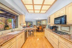 Une cuisine spacieuse dotée de plans de travail en granit, d’armoires en bois et d’un îlot central.