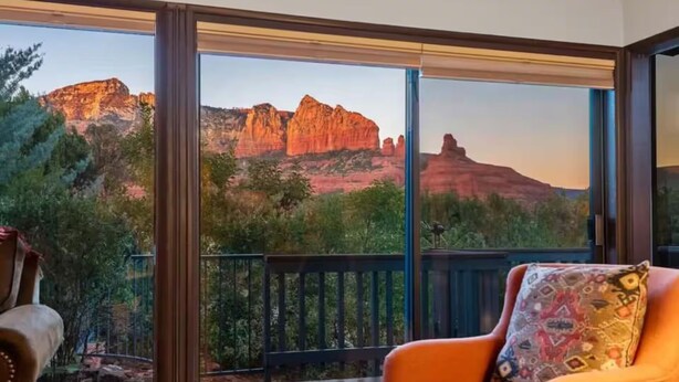 Ein Zimmer mit großem Fenster und Blick auf rote Felsenformationen und Grünpflanzen.