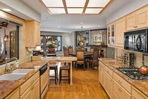 A kitchen with a central island, wooden cabinets, a stove, and a dining area with chairs. - 3 King Suites Walk to Uptown Views & Trails (Sedona)
