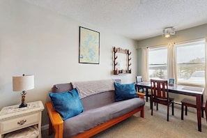 Ein gemütliches Zimmer mit einer Couch, einem Esstisch und einer Karte an der Wand.