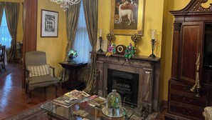 A room with a fireplace, a chandelier, a framed painting, and a wooden cabinet. - 1896 O'Malley House (New Orleans)