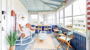 A covered porch with rocking chairs, a table, and a potted plant. - Ocean Point Cottage- large porch, ocean view, water access (East Boothbay)