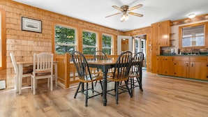 Un intérieur en bois comprenant une table à manger, des chaises et un ventilateur de plafond.