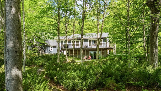 Une zone boisée avec un bâtiment à plusieurs étages et doté de balcons, entouré d’une végétation luxuriante et d’arbres.