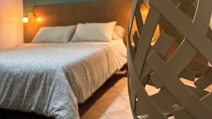 A bedroom with a bed, a wall-mounted light, and a decorative wall piece.