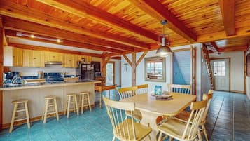 Une cuisine spacieuse dotée de meubles en bois, d’un îlot central avec des tabourets et d’un coin repas avec une table et des chaises.