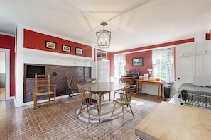 Un espace repas avec un sol en briques, une cheminée et une table à manger entourée de chaises.