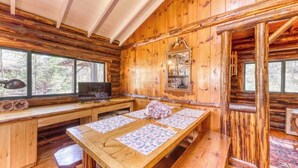 A wooden cabin interior with a long dining table, a television, and a mirror on the wall.