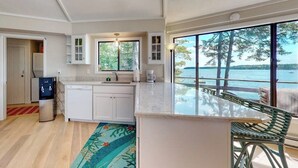 A kitchen with a large island, a refrigerator, and a view of the water.