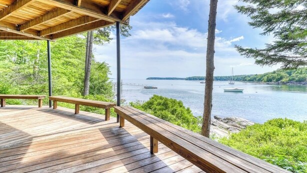 A wooden deck with benches overlooking a body of water and a distant shoreline.