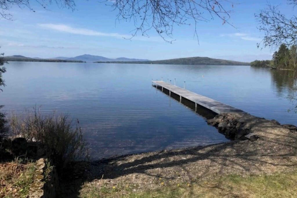 Un lac paisible, avec une jetée en bois qui s’avance sur l’eau.