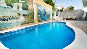 A swimming pool with a mural, lounge chairs, and a concrete wall. - A fully furnished, Beachside Apartment | Pool, Walk Everywhere (Calle Almirante)