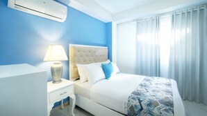 A hotel room with a bed, a nightstand, a lamp, and a window with curtains. - A fully furnished, Beachside Apartment | Pool, Walk Everywhere (Calle Almirante)