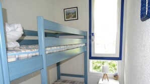 Habitación con literas, una pequeña mesita de noche y un cuadro en la pared.