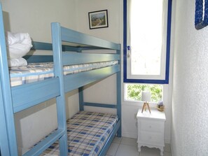 Ein Schlafraum mit Etagenbett, einem kleinen Nachttisch und einem gerahmten Bild an der Wand.