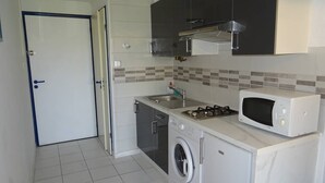 Una cocina compacta con lavadora, microondas y estufa a gas.