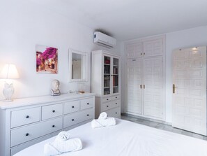 Ein Schlafzimmer mit einem Bett, einem Schminktisch, einem Spiegel, einem Kleiderschrank und einer Klimaanlage.