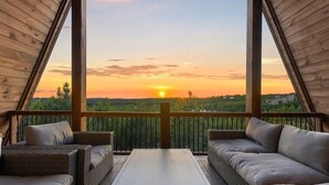 Um deck ao ar livre com móveis de vime e vista para o pôr do sol.