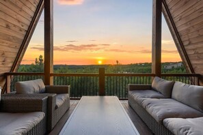 Eine Terrisse im Freien mit Korbmöbeln und Blick auf den Sonnenuntergang.