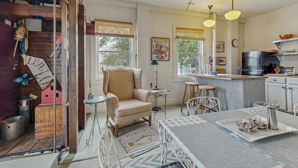 A cozy kitchen with a dining area, wooden beams, and a large window. - Sunrise on the Sheepscot- condo w/ deck overlooking the water - steps to dining & shopping (Wiscasset)