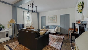 A living room with a sofa, armchair, and a patterned rug. - Sunrise on the Sheepscot- condo w/ deck overlooking the water - steps to dining & shopping (Wiscasset)