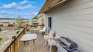 A deck with outdoor furniture, a grill, and a view of the water and train tracks. - Sunrise on the Sheepscot- condo w/ deck overlooking the water - steps to dining & shopping (Wiscasset)