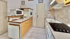 Eine kleine Küche mit Mikrowelle, Kaffeemaschine, Backofen, Spüle und Herd.