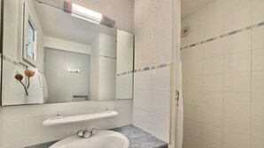 Une salle de bain avec un lavabo blanc, un miroir et une douche.
